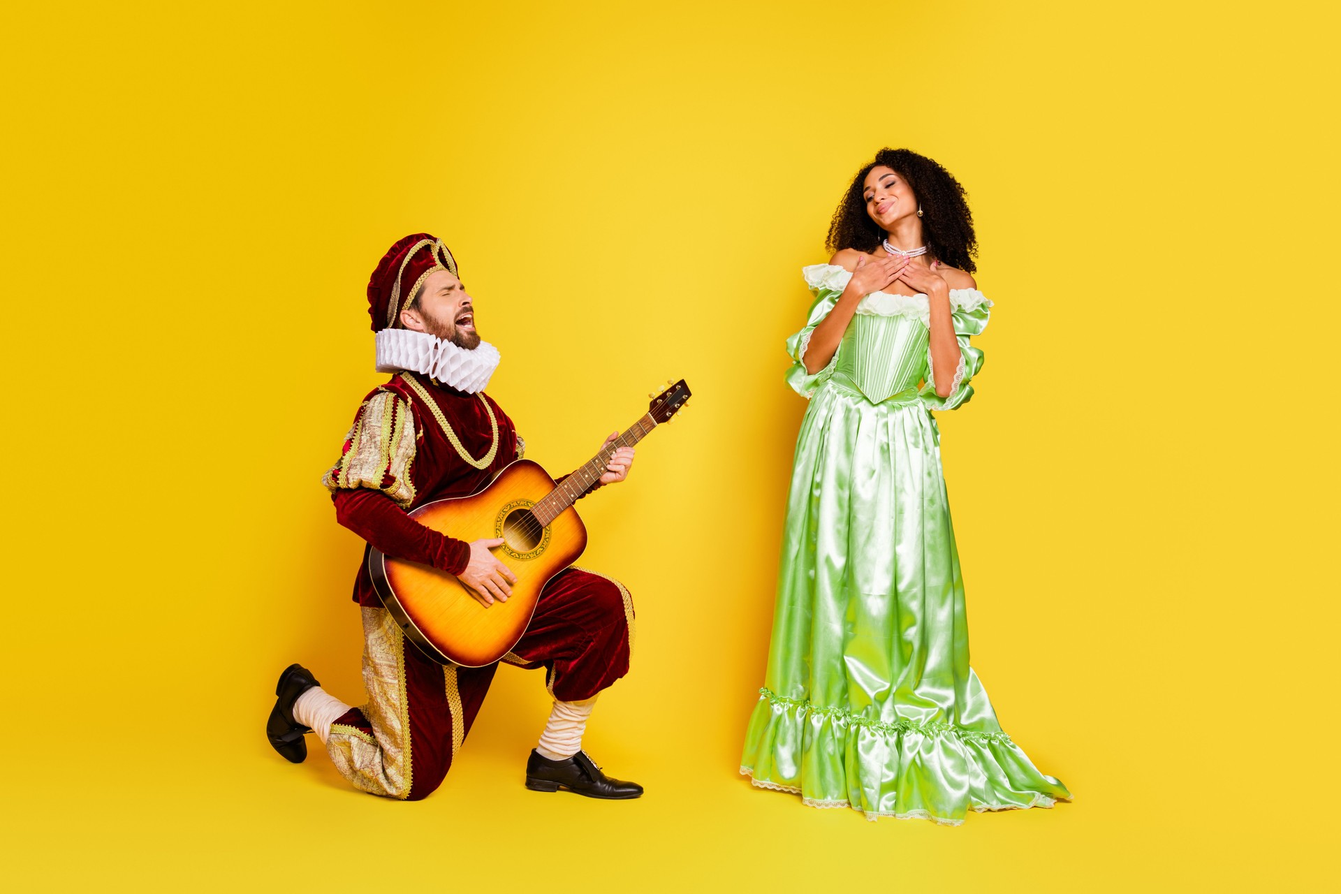 Pareja en trajes reales posando contra fondo amarillo vibrante en la representación del tema